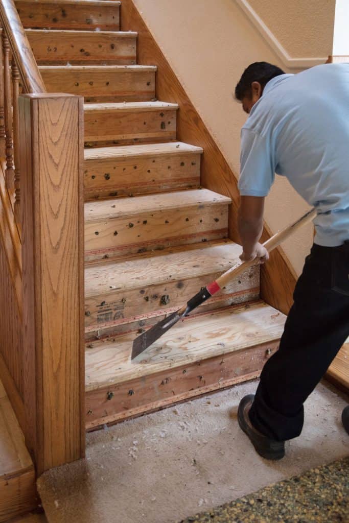 A man cleaning the stairs before installing carpet