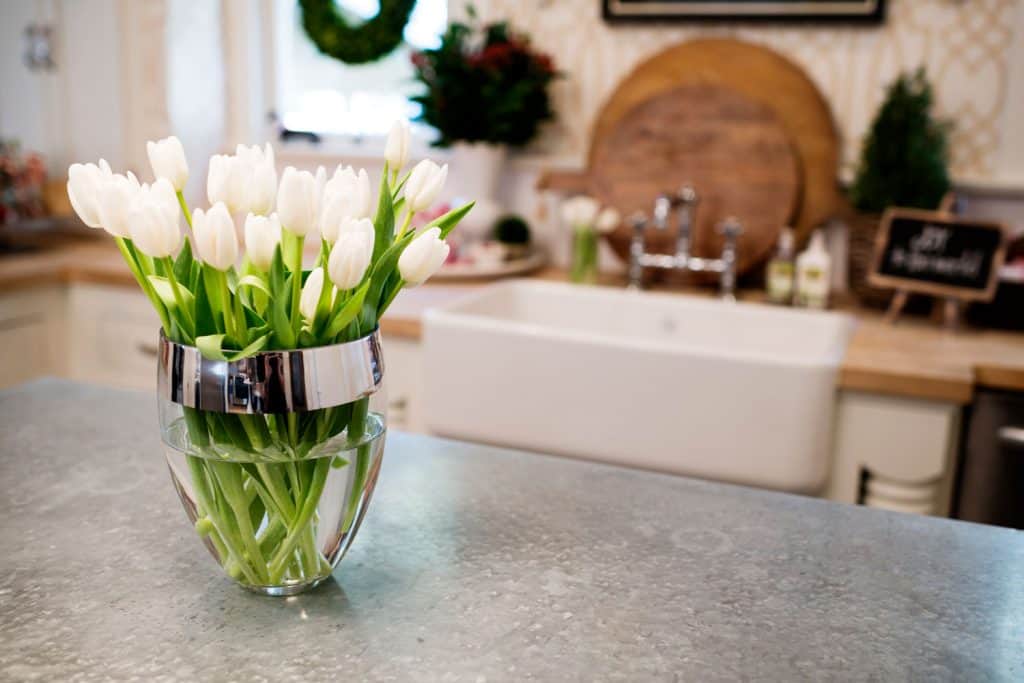 A small glass vase inside the bathroom with gorgeous white tulips