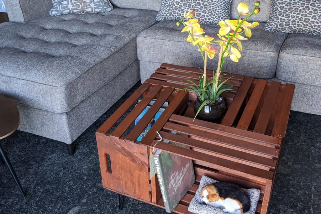 A small wooden coffee table with an orchid on a vase properly aligned to the sectional sofa