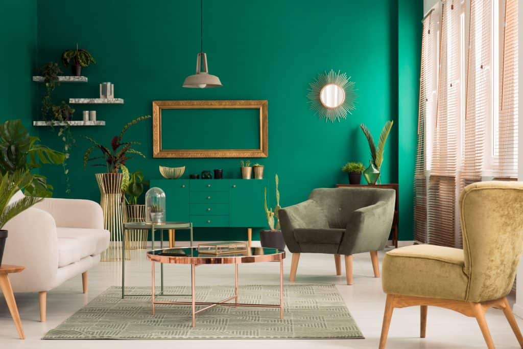 A teal mid century inspired living room with a green accent wall, beige and green furniture's, and incorporated with a golden coffee table