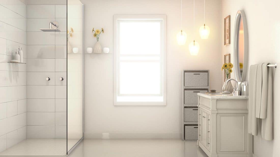 An interior of a modern bathroom with pale cream walls a shower vanity and mirror and backlit window