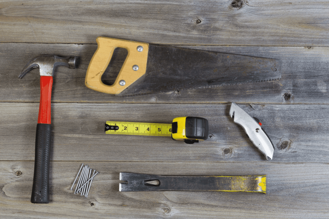Basic Hand Tools for Home Repair laid out on a wood plank table