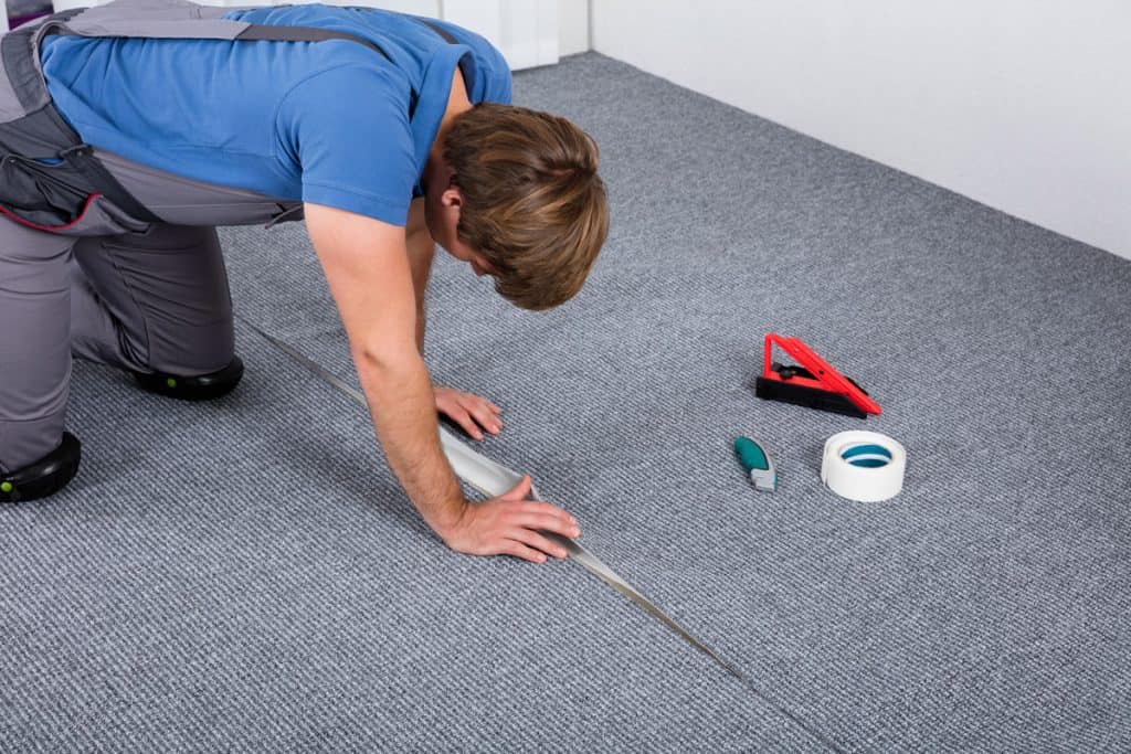 Carpet installer folding and inserting the excess carpet