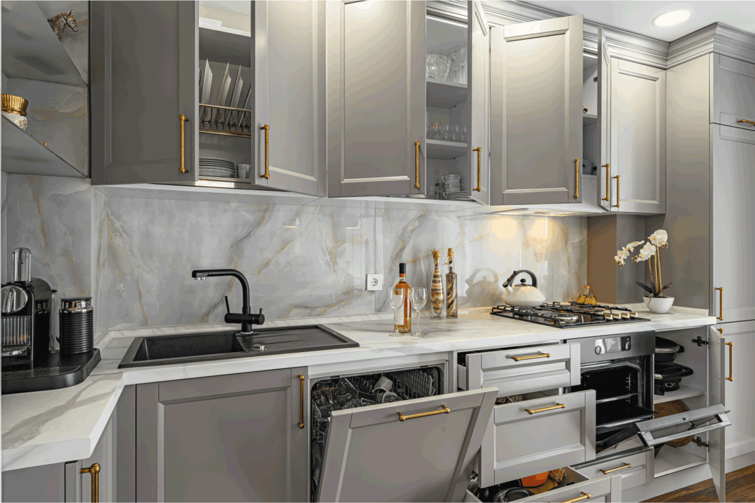 Closeup details of grey and white contemporary classic kitchen designed in modern style, all furniture doors and drawers are open
