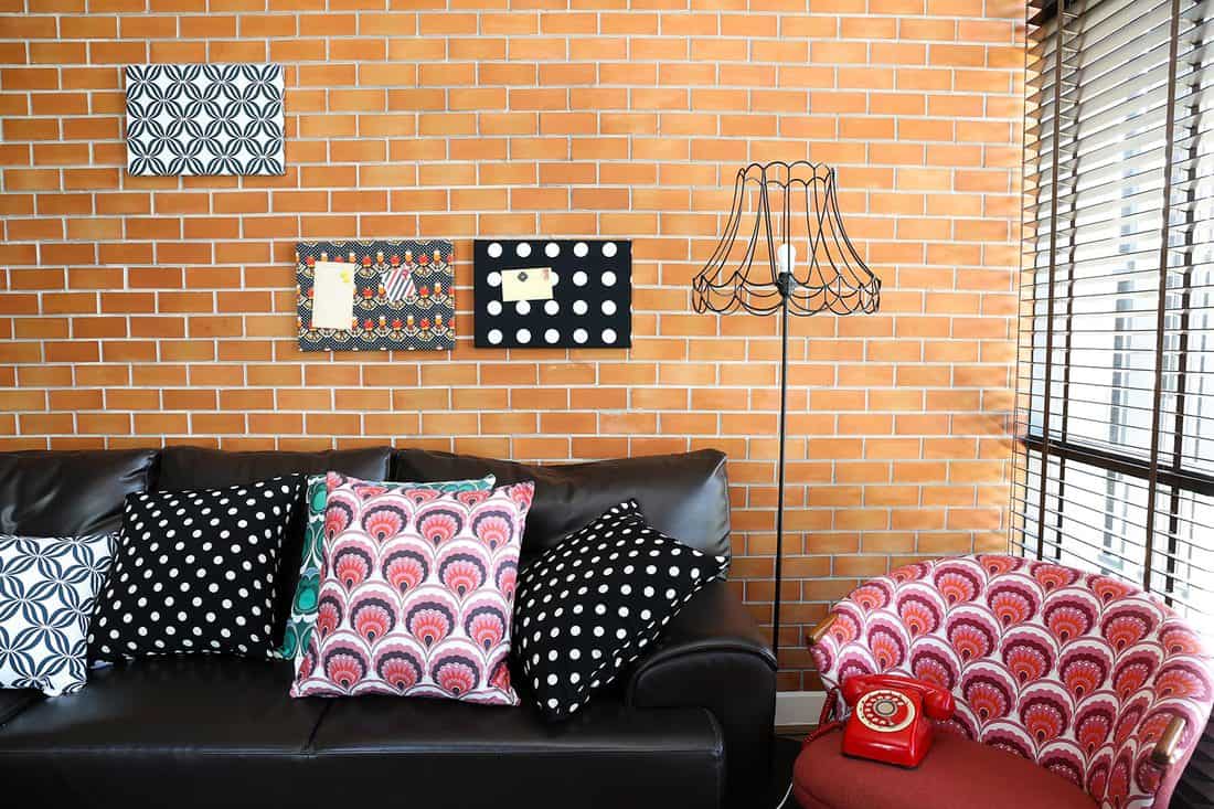 Colorful pillows on a sofa with brick wall in background