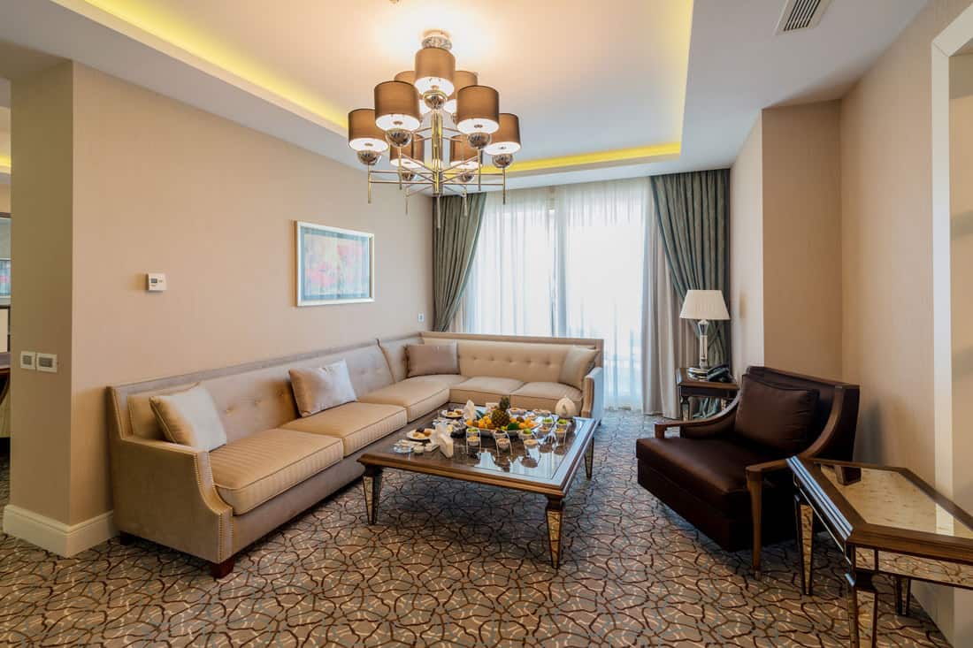Gorgeous tan living room with a chandelier on the center and carpeted flooring with cream furnitures, What Color Walls Go With Cream Or Tan Trim?