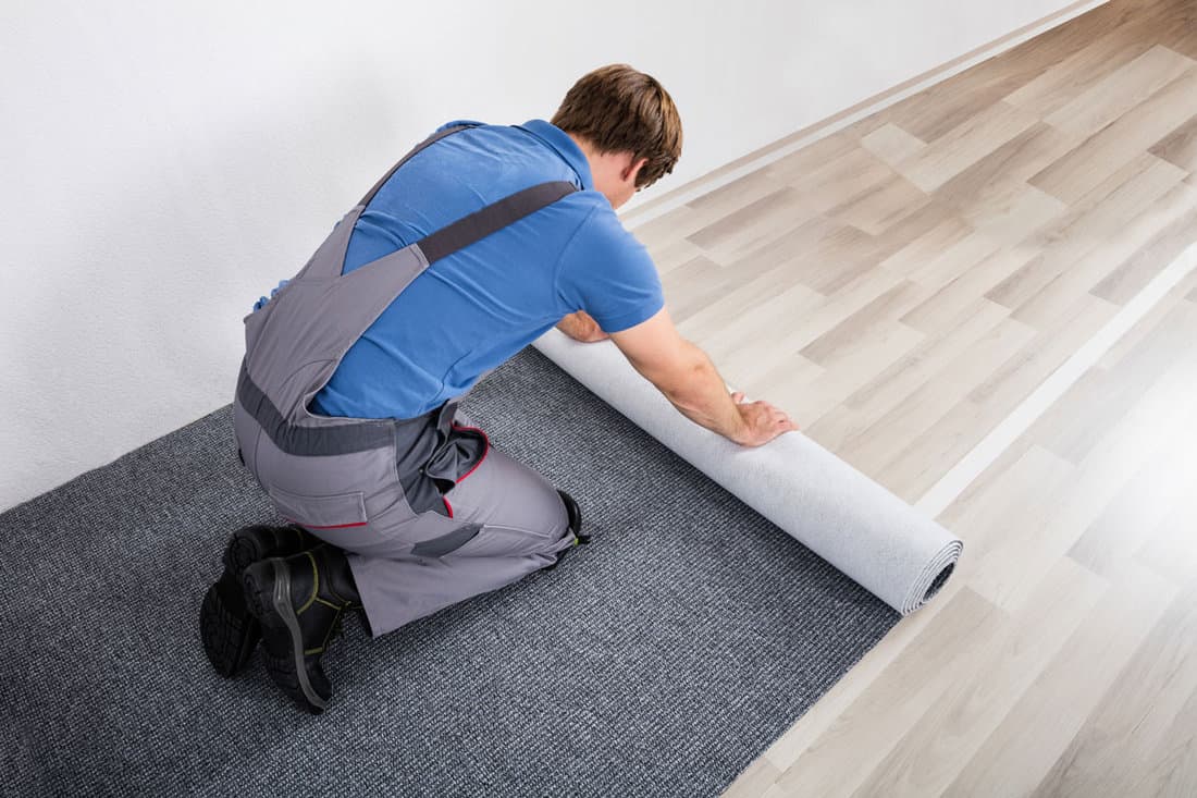 Handyman Rolling Carpet On Floor
