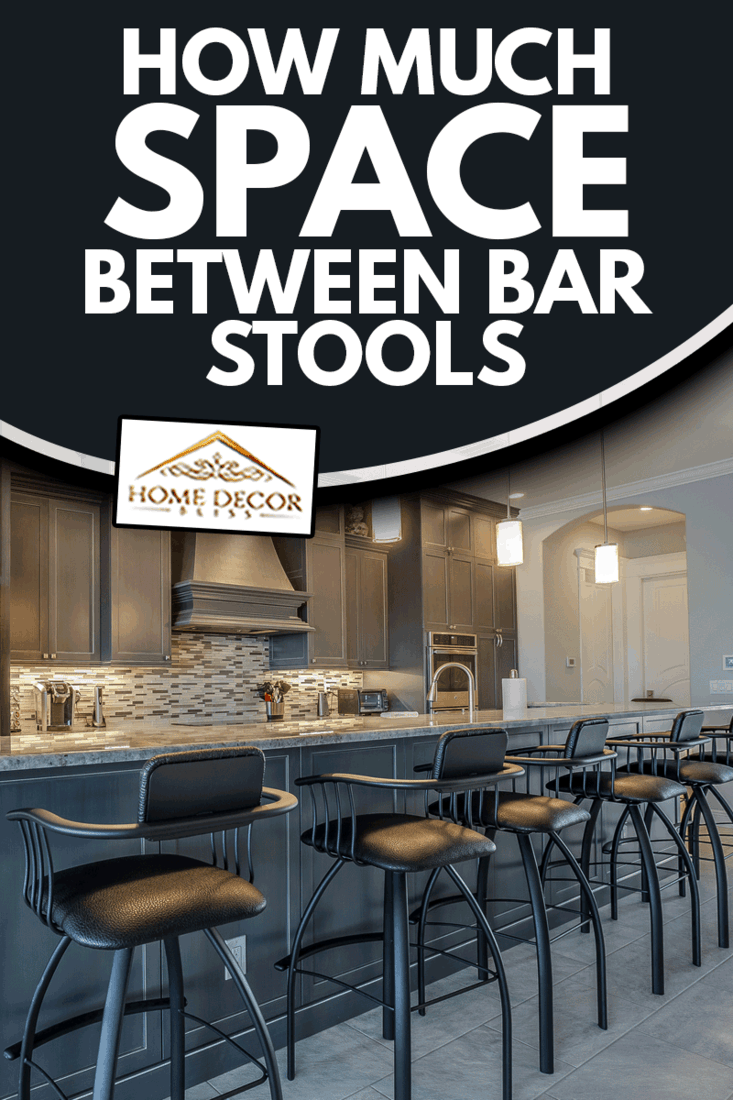 Dark gray cabinets and pendant lights adorn this classy kitchen with bar stools, How Much Space Between Bar Stools?
