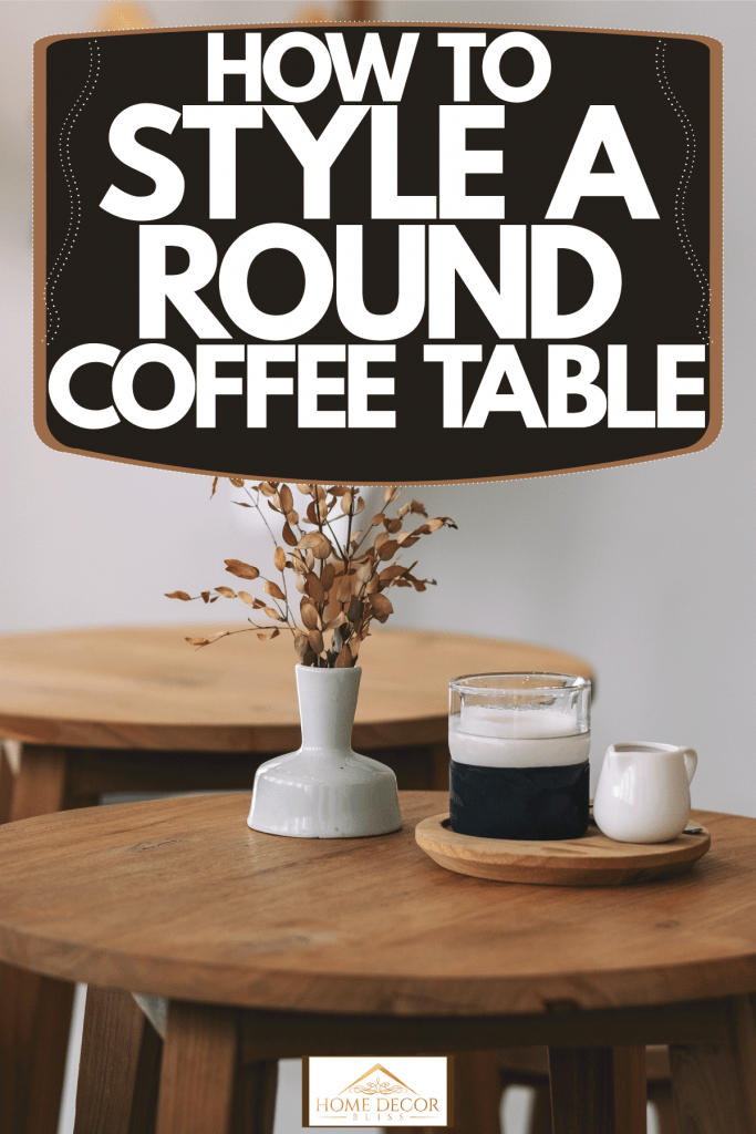A wooden coffee table with a small vase with small flowers, How To Style A Round Coffee Table