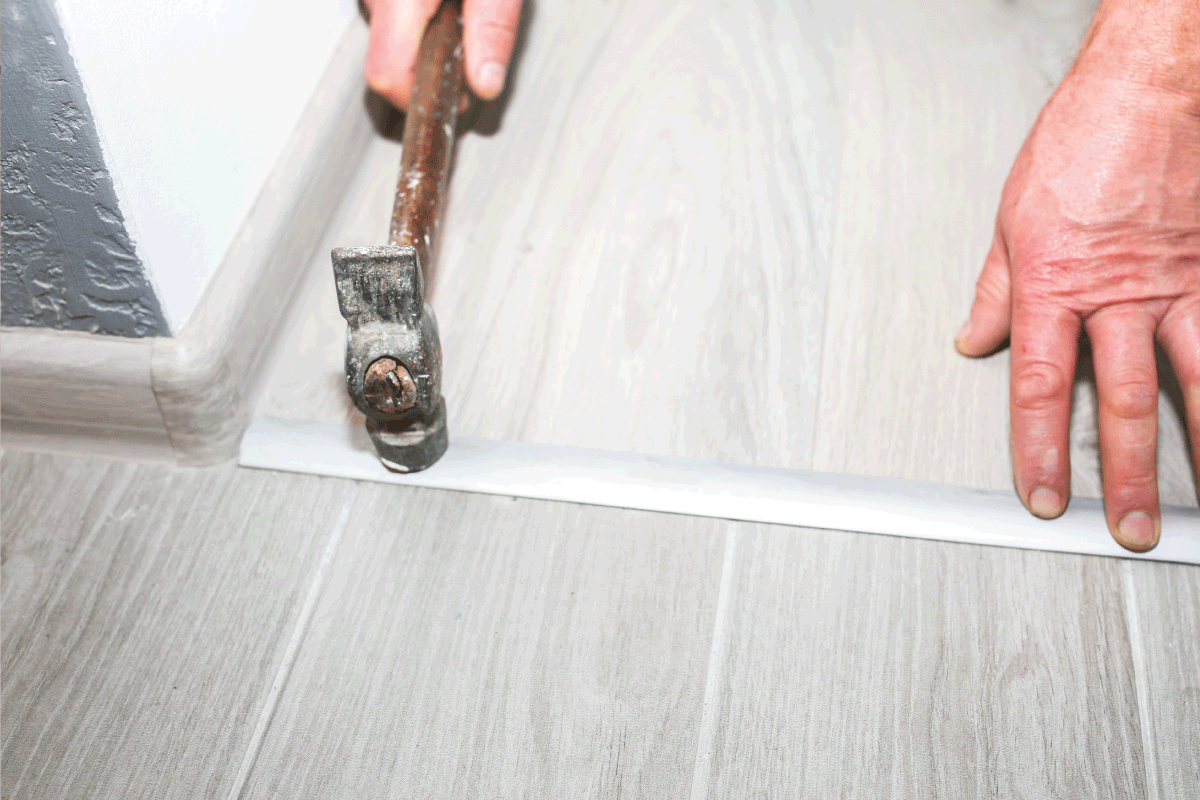 Installation of threshold indoors. Renovation works in the flat. Man with a hammer.How To Make Tile Flush With Hardwood Floor