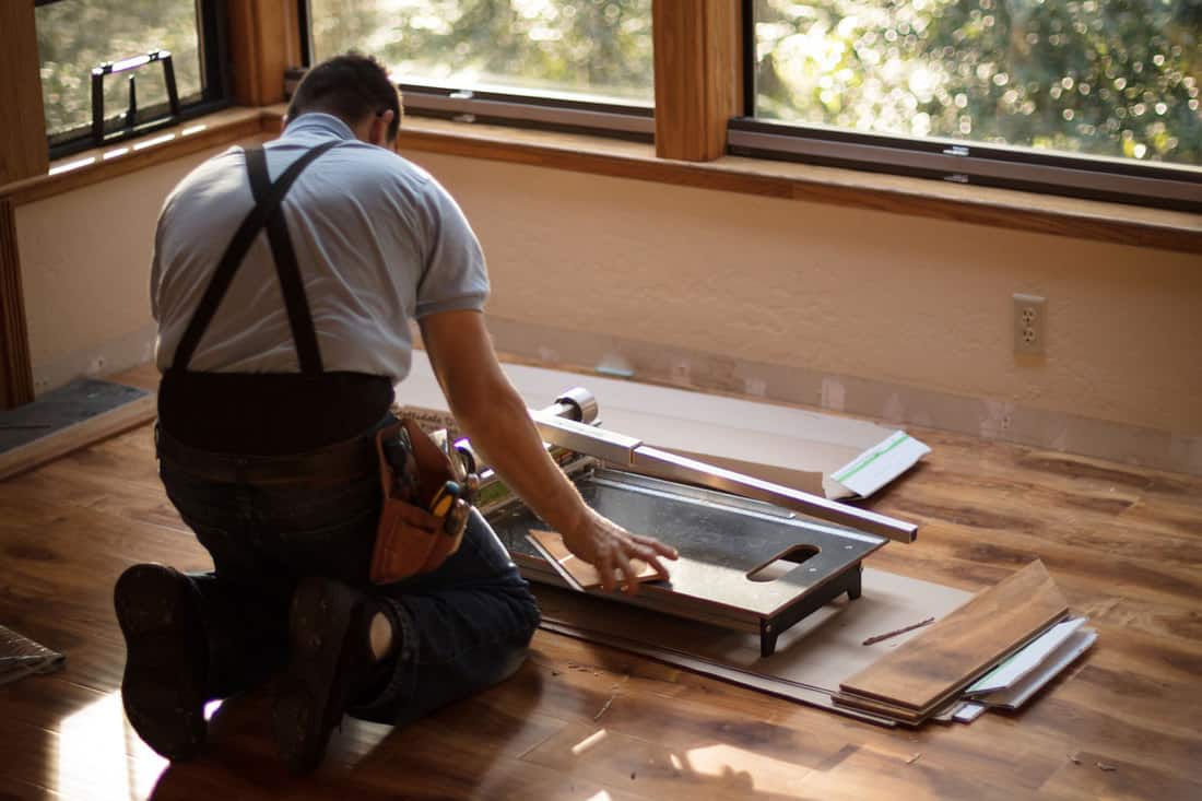 Man installing wood flooring in home, How To Cut Hardwood Floors Near A Wall