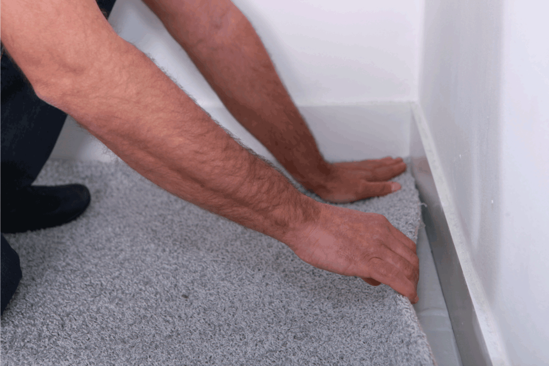 Man-putting-in-carpet.-How-To-Lay-Carpet-Over-Laminate-Flooring-[A-Complete-Guide]