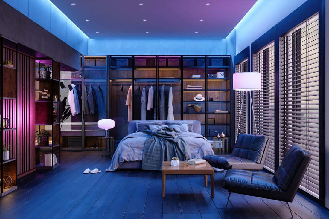 Modern Bedroom Interior At Night With Neon Light. Messy Bed, Clothes In Closet, Armchairs And Floor Lamp, Why Does My Bedroom Get So Hot At Night? [And What To Do About It]