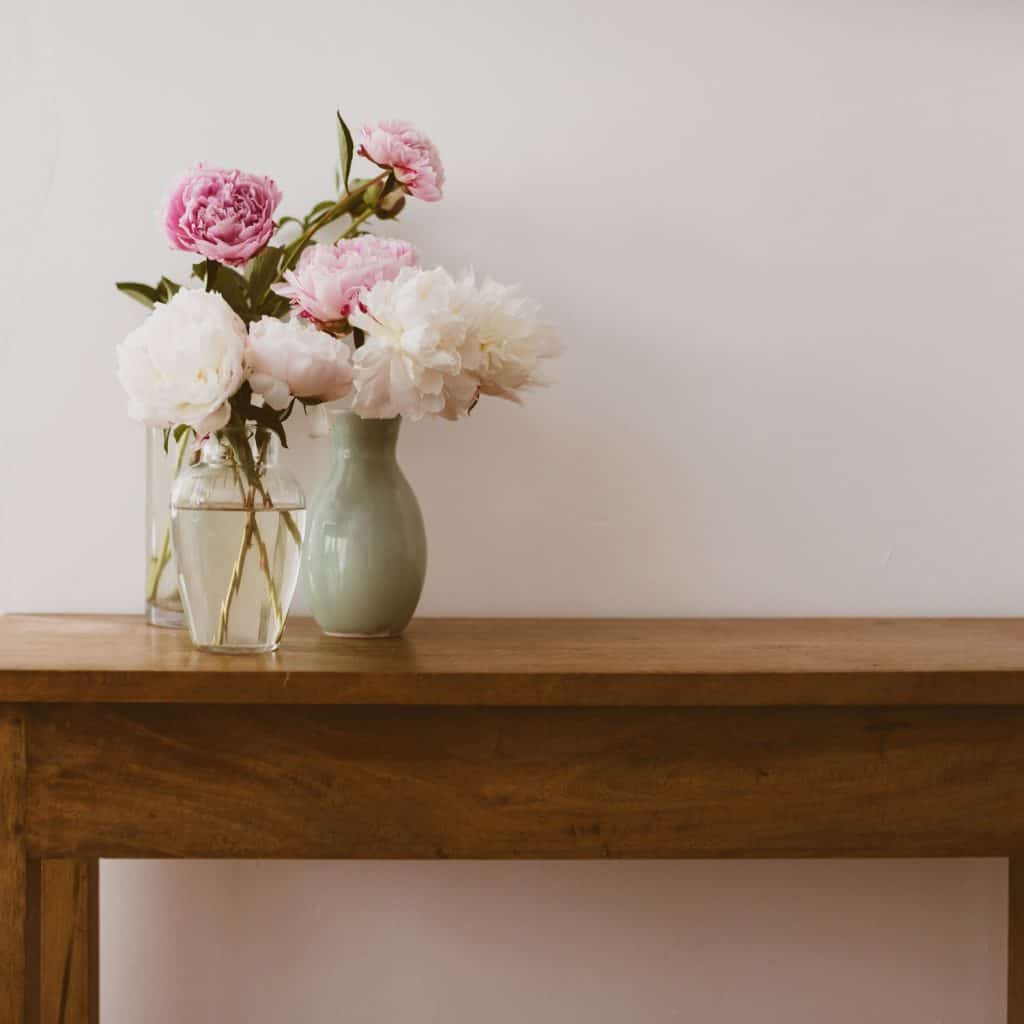 Pink and white peonies on top of a wooden table