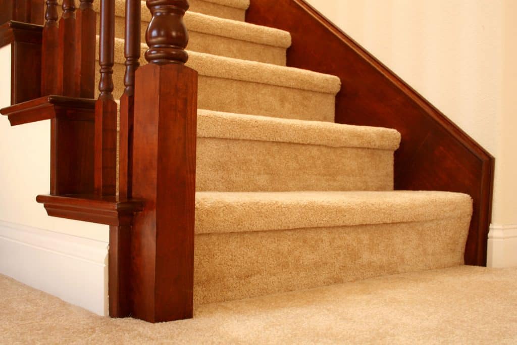 Stairs with carpeted flights and a wooden stair railing