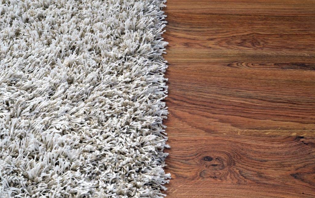 Two part split image of white shaggy carpet and brown wooden floo
