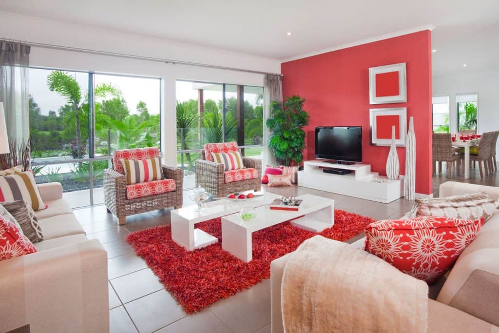 Velvet inspired living room with red throw pillows carpet and a red accent wall with indoor plants