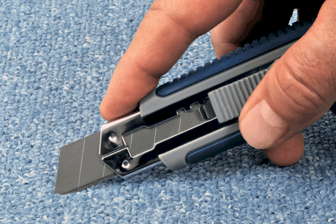carpet being cut using a cutter on hand