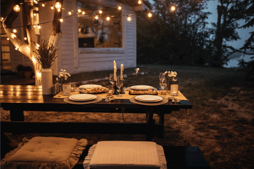 Shot of a nicely set table awaiting guests for dinner in a backyard with hanging string lights from a tree. How To Hang String Lights In A Lanai