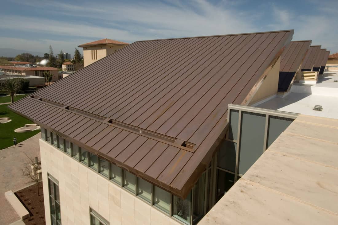 A brown pre-painted metal roof of a luxurious residential house, What Color House Goes With A Metal Roof?