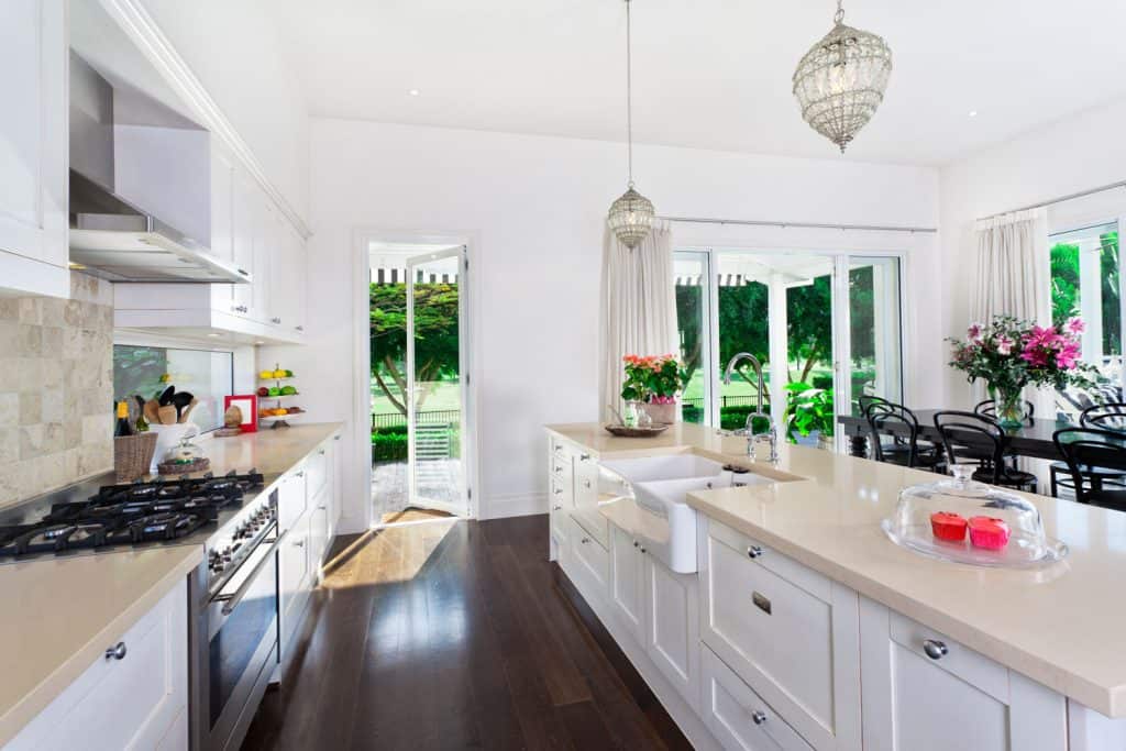 A white inspired kitchen with dark flooring, white cupboards, and drawers