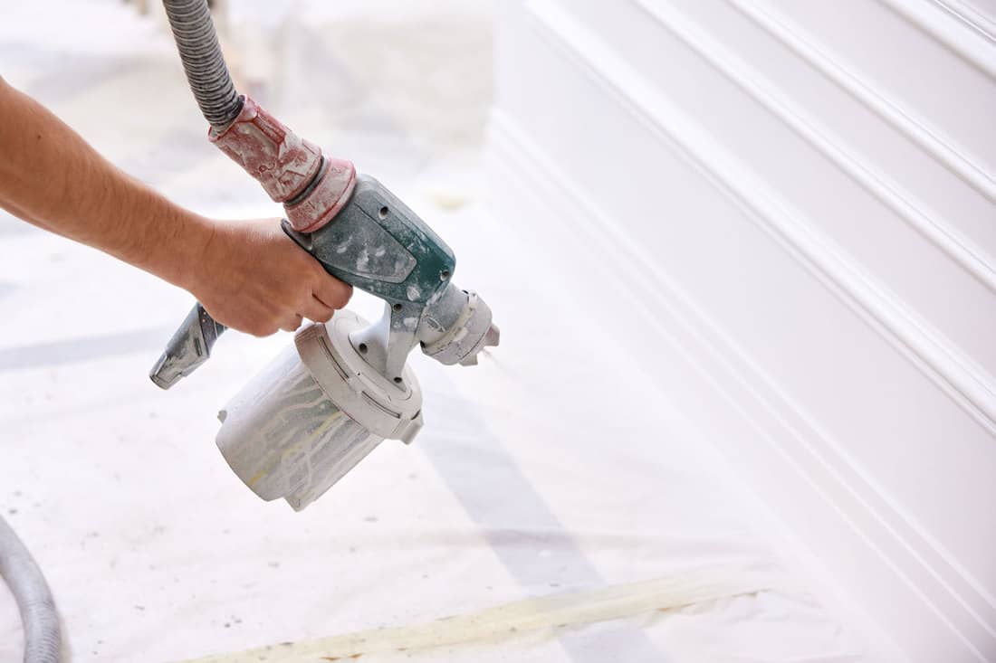 A worker using a sprayer to paint the room white, How To Paint A Room With A Sprayer