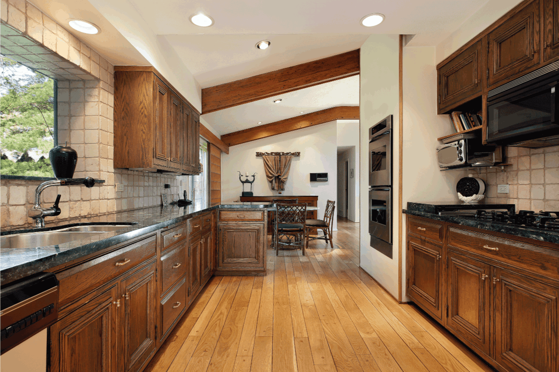 Kitchen with wood cabinetry and oak flooring. What Color Cabinets Go With Oak Floors