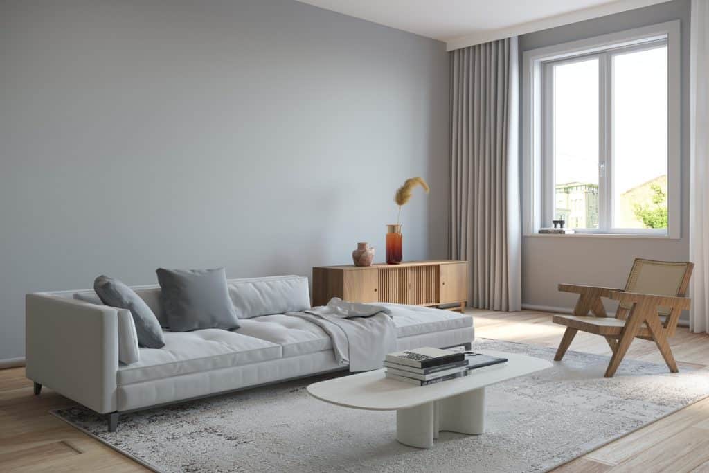 Living room interior with gray sofa and wooden armchair, carpet on the floor and white coffee table. Render image.