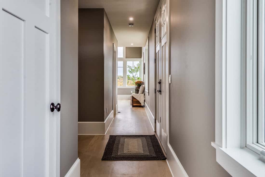 Luxurious rustic inspired hallway with dark gray painted walls, laminated flooring and white doors
