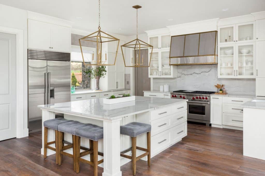 Luxury themed kitchen with wooden plank flooring, white cupboards and cabinets with white marble countertops