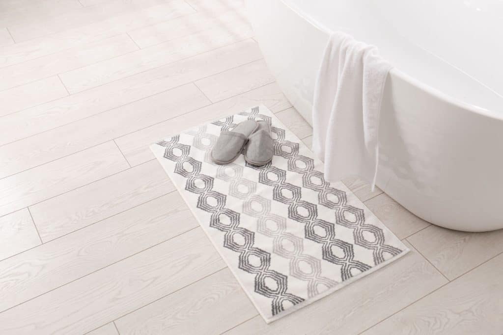 White patterned rug next to a white bathtub