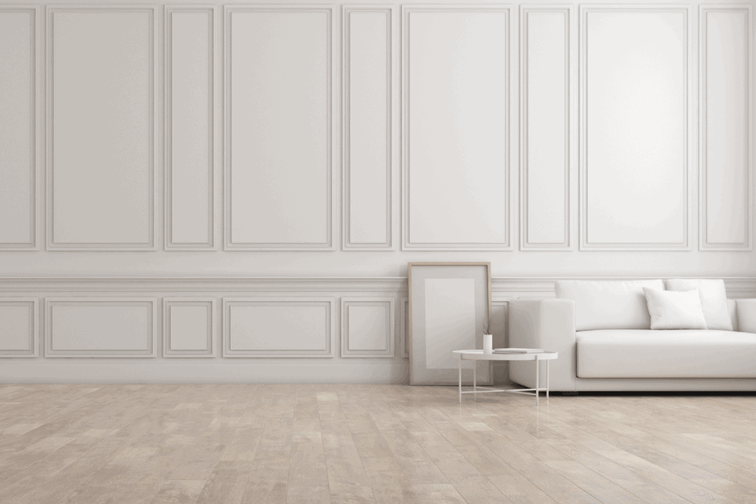 white living room in classic style with furniture on bright laminate floor ang raised wall panelling. 