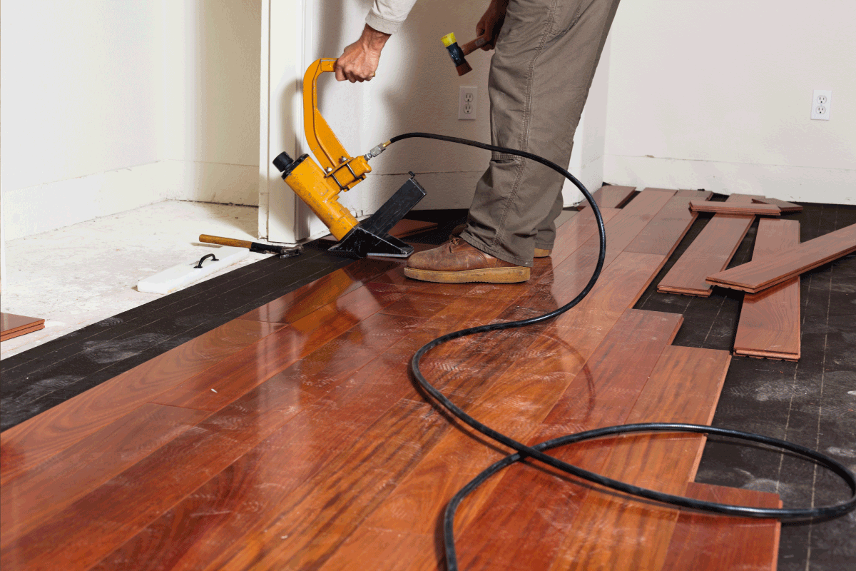 A worker installing hardwood floor in an American upscale home using a pneumatic nail gun. What Type And Size Of Nails For Hardwood Floors