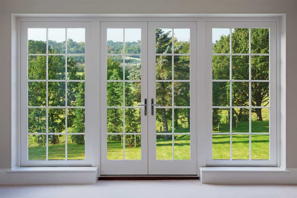 A huge double French door with window panes going to the outdoor trees