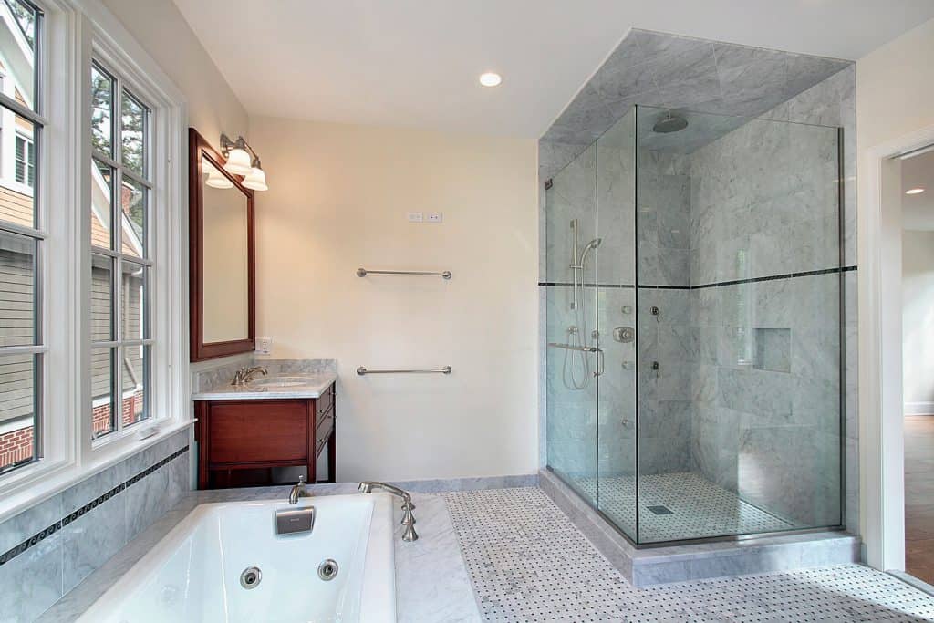 A long span shower area with glass shower walls inside a classic styled modern bathroom