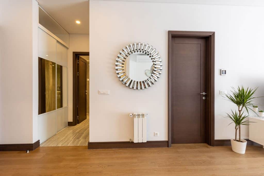 A round mirror next to a brown colored bedroom door