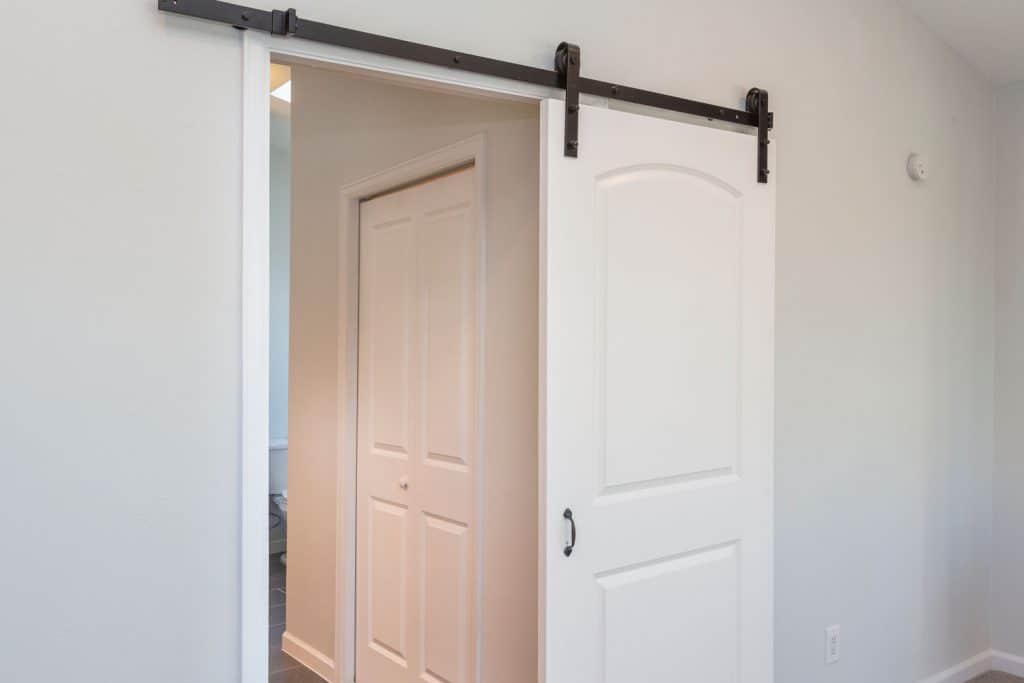 A white barn door leading to the bedroom