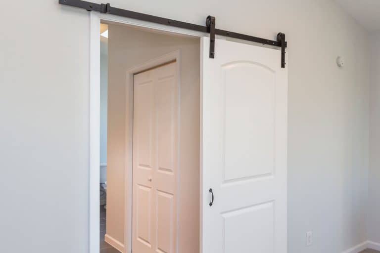 A white barn door leading to the bedroom, How To Keep Barn Doors From Sliding Open