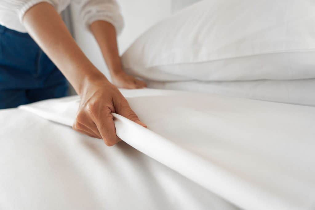 A woman replacing the bed sheets in her bedroom