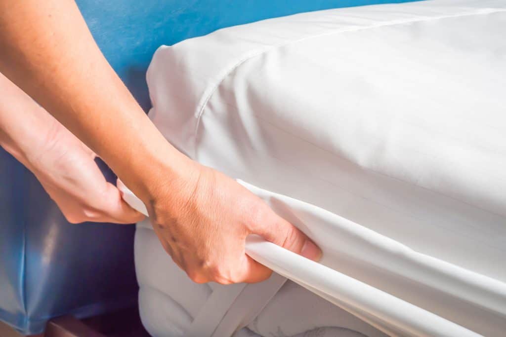 A womans hands replacing the bedsheets