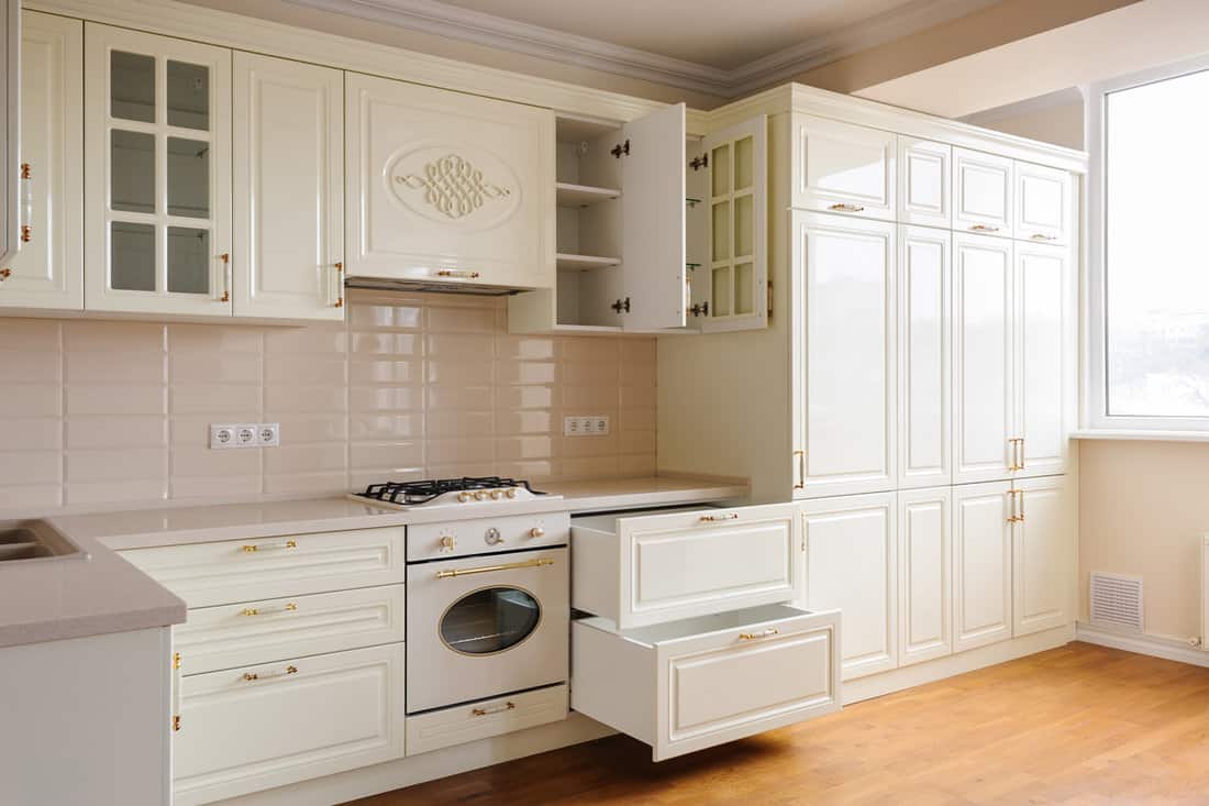 Cream cabinets of a kitchen with white countertops and wooden flooring