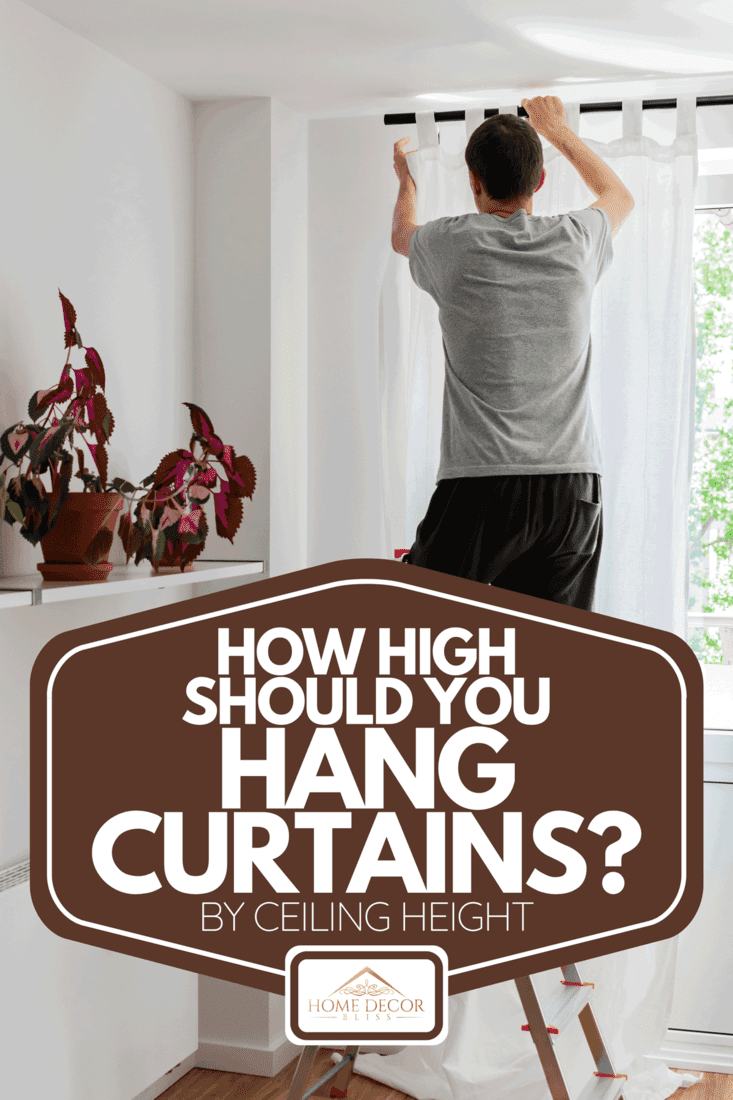 A young man installing curtains over window, How High Should You Hang Curtains? [By Ceiling Height]