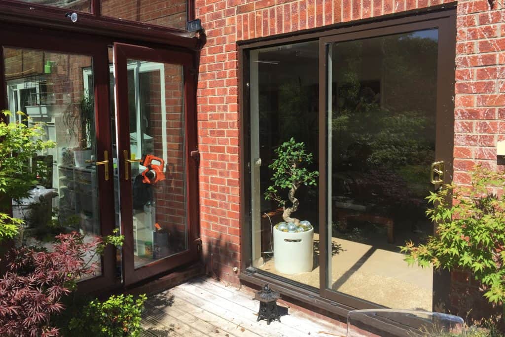 A glass sliding door of a two story house leading to the garden