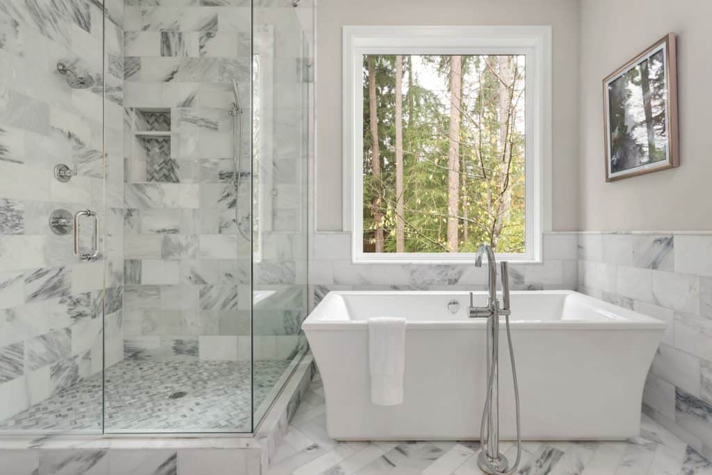 A stone tiled bathroom from walls and flooring with a rectangular bathtub