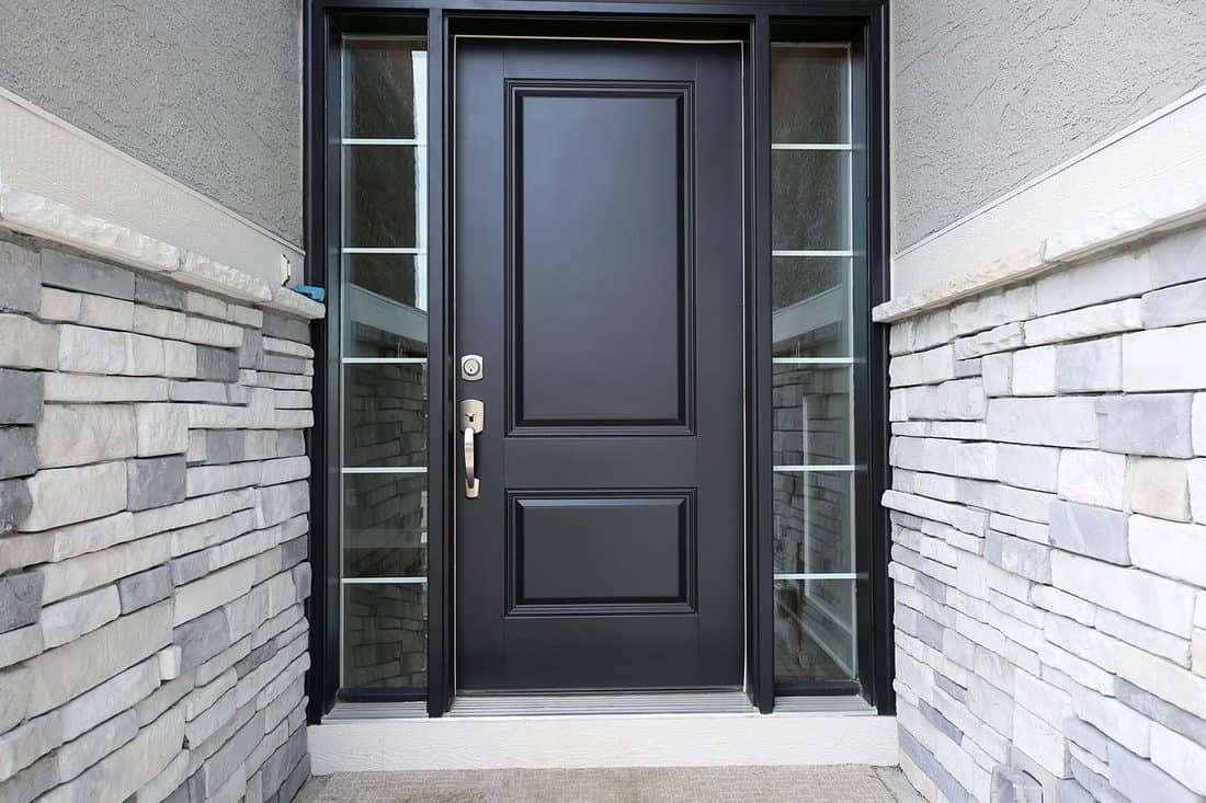 Black front door with stone wall