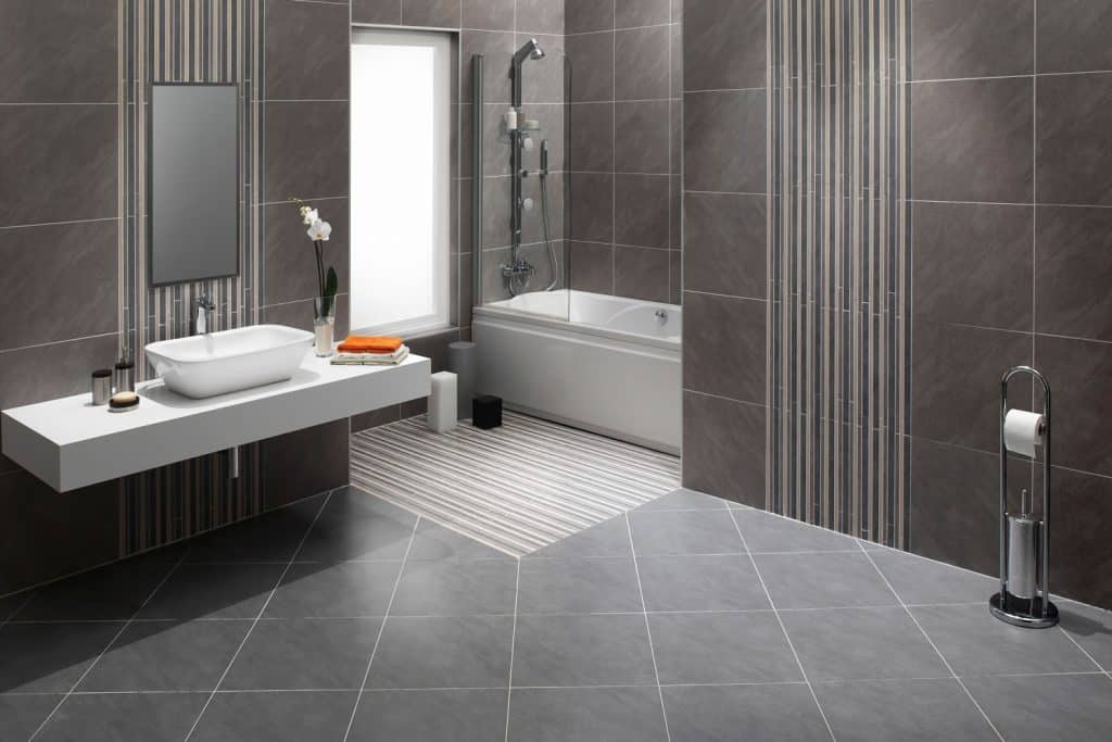 Contemporary themed bathroom with gray tiled flooring, gray tiled walls and a bathtub