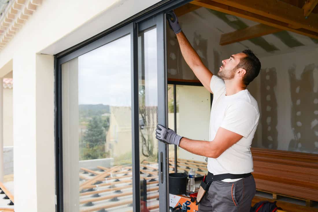Handsome young man installing sliding door in a new house construction site