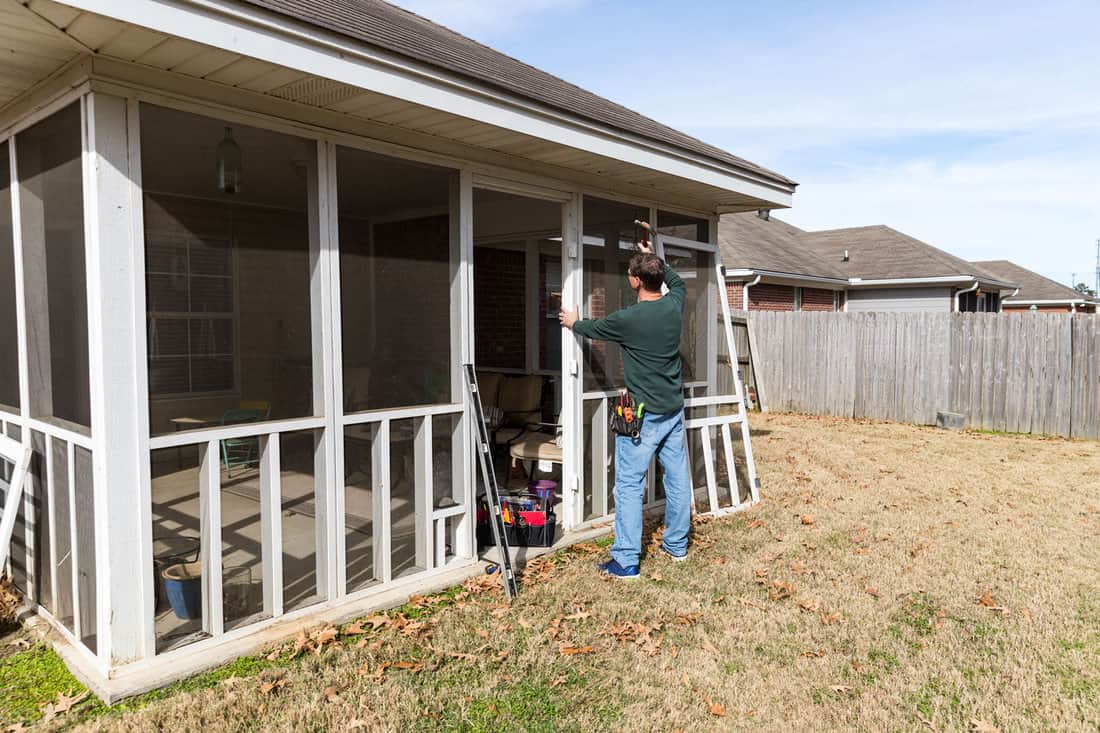 Homeowner works on repairing door to screened in back porch 