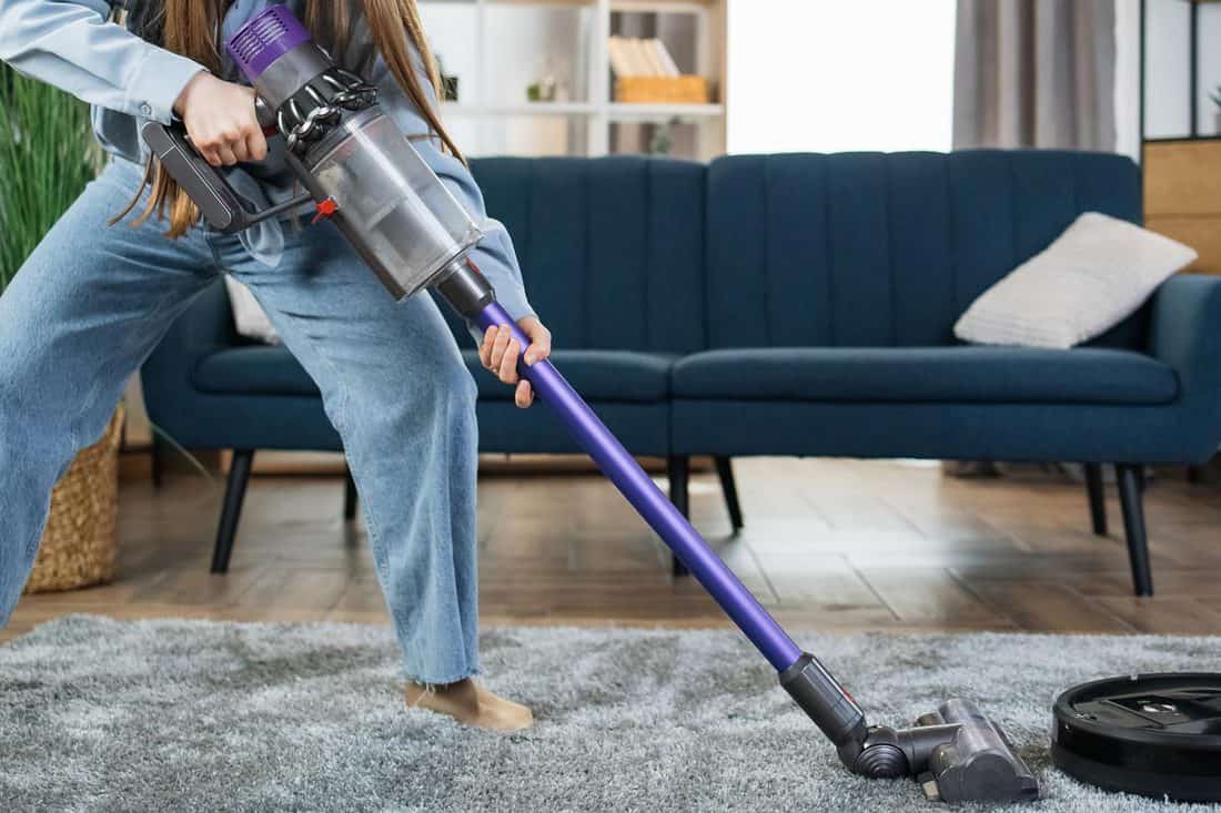 Woman cleaning house with modern vacuum cleaners