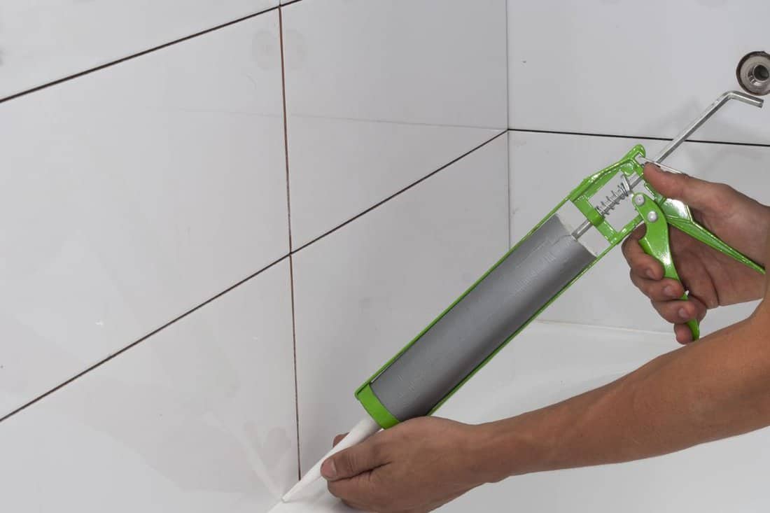 plumber apply silicone sealant to the joint bathtubs and ceramic tile